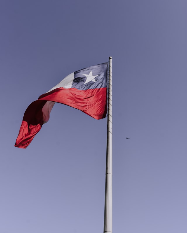 Imagem da bandeira do Chile tremulando num dia de céu azul e tempo aberto