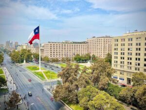 Vista da Plaza de La Ciudadania com a bandeira do Chile hasteada e poucos carros circulando