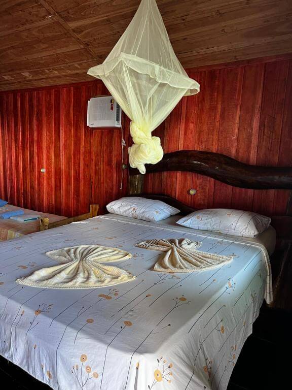 Quarto do Amazônia Exxperience Lodge, em Manaus no Amazonas, com uma cama de casal, ar-condicionado, toalhas, mosqueteiro