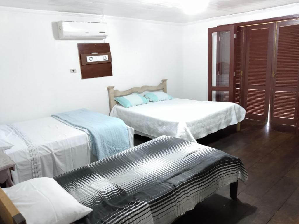 Quarto da Casa na Beira do Rio, em Morretes no Paraná, com uma cama de solteiro e duas de casal, além de ar condicionado