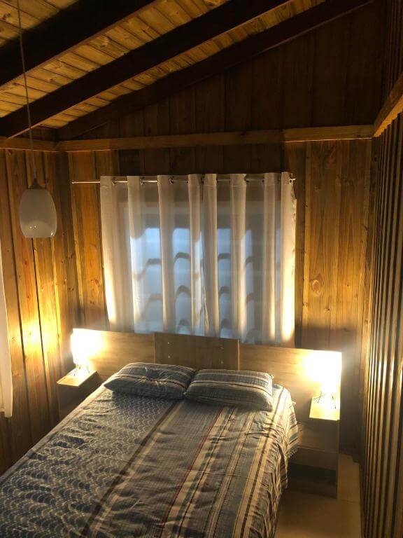 Quarto da Chacará Porto Belo, em Morretes no Paraná, com cama de casal, travesseios, janela e luminárias