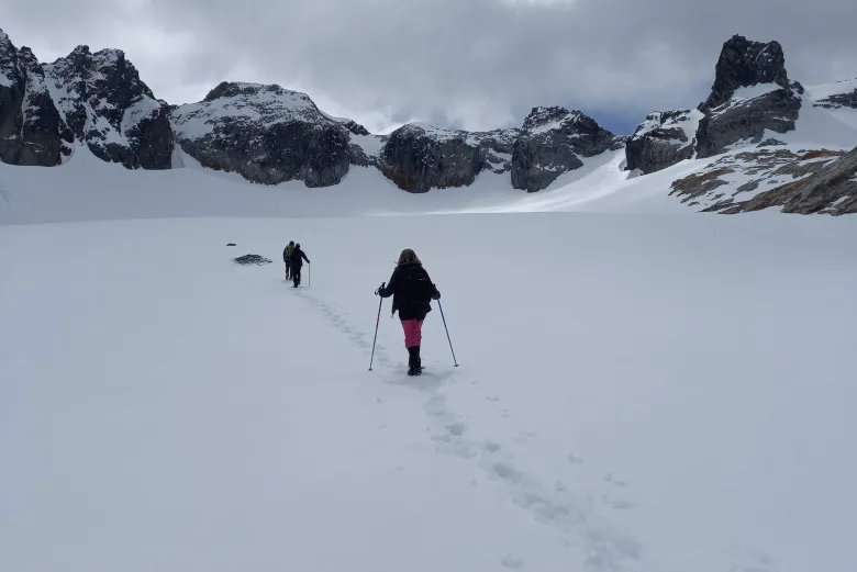 Pessoas fazem trilha na neve no Glaciar Ojo del Albino em Ushuaia na Argentina durante um dia de céu encoberto