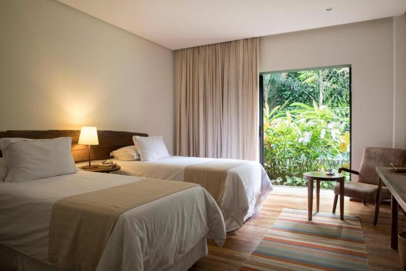 Quarto do Hotel Villa Amazônia, em Manaus no Amazonas, com camas de casal, poltrona, mesa de centro, luminária