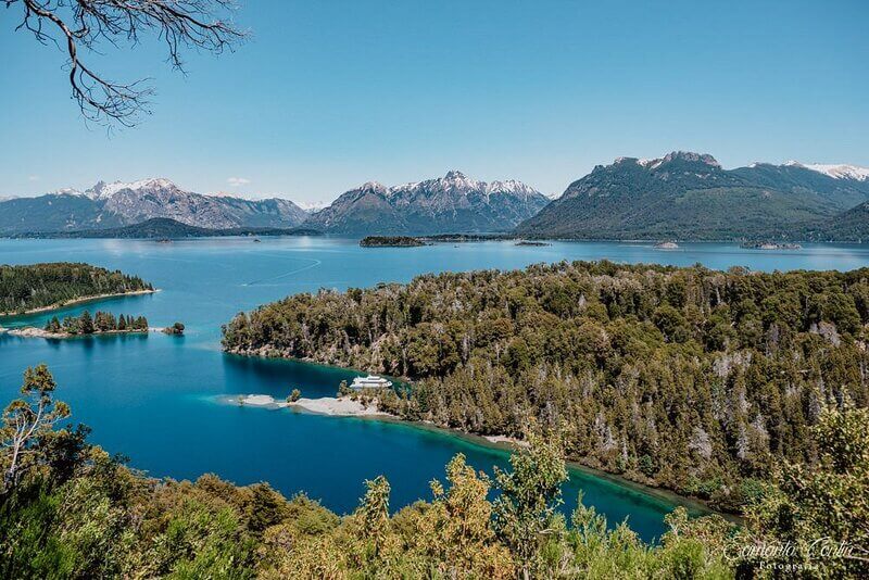 Lago e montanhas da Isla Victoria e Bosque de Arrayanes em Bariloche na Argentina druante um dia de sol e céu claro. Reprodução: Tripadvisor.