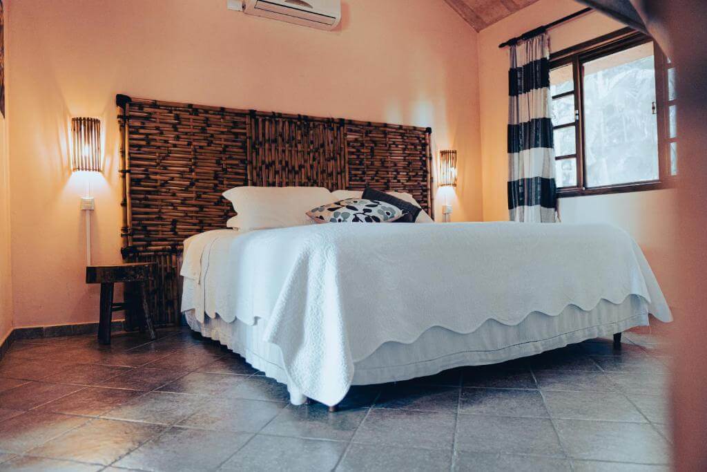 Quarto das Casas Di Monte Ecopousada, em Morretes no Paraná, com cama de casal, luminárias, ar-condicionado, piso em azuleijo