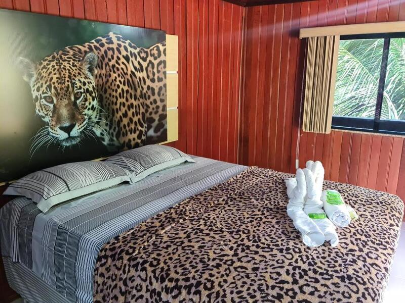 Quarto da Pousada e Restaurante Amazonia, em Alter do Chão no Pará, com cama de casal, toalhas e um quadro com imagem de onça pintada