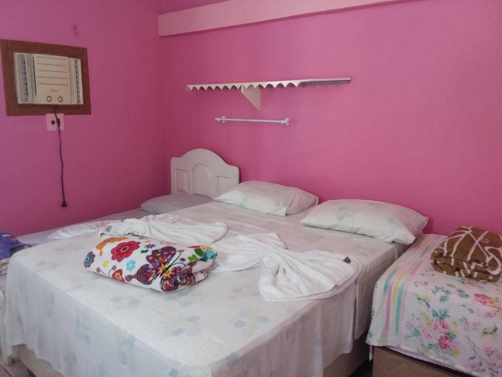 Quarto da Pousada Ponta das Pedras, em Alter do Chão no Pará, com cama de casal e solteiro, ar-condicionado com decoração rosa