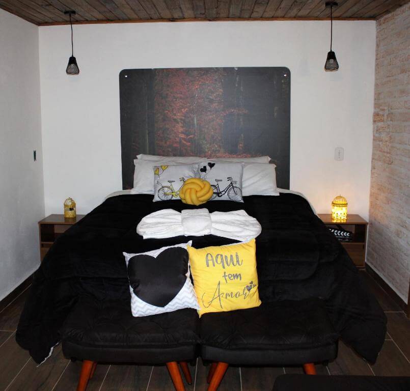 Quarto do Recanto Lira, em Monte Verde - MG, com cama de casal, travesseiros e mesas de cabeceiras em ambos os lados
