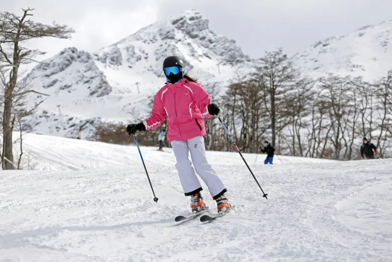 Mulher com jaqueta rosa e calaça branca esquai em Cerro Castor em Ushuaia na Argentina