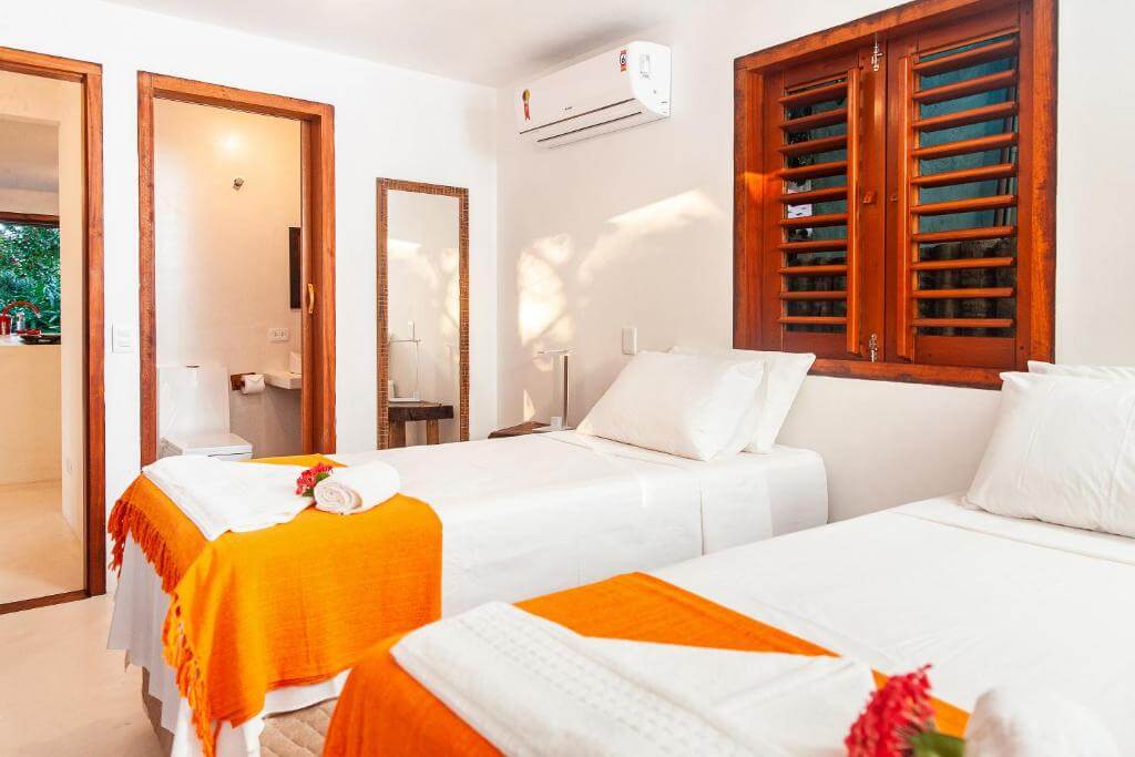 Quarto do Mirante Caraíva, em Caraíva na Bahia - BA, com ar-condicionado, camas de solteiro, banheiro, toalhas, espelho e janela