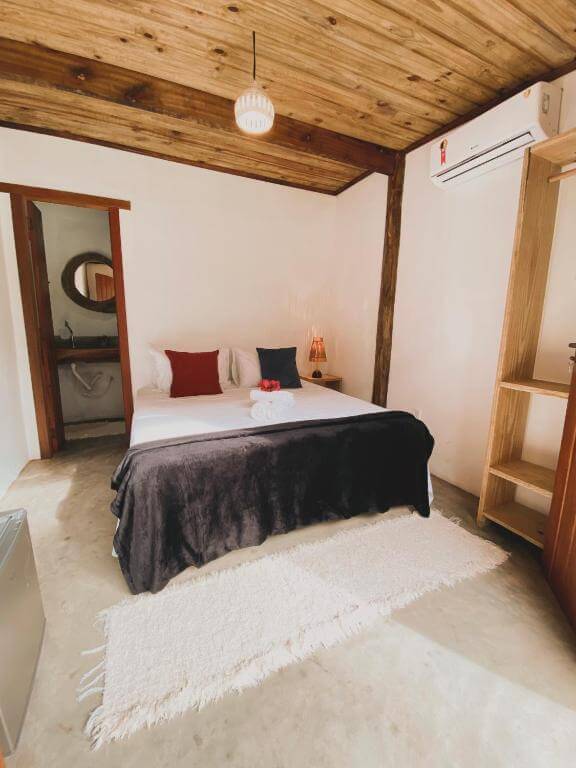 Quarto da Pousada Dendê Caraíva, em Caraíva na Bahia - BA, com cama de casal, banheiro e ar-condicionado