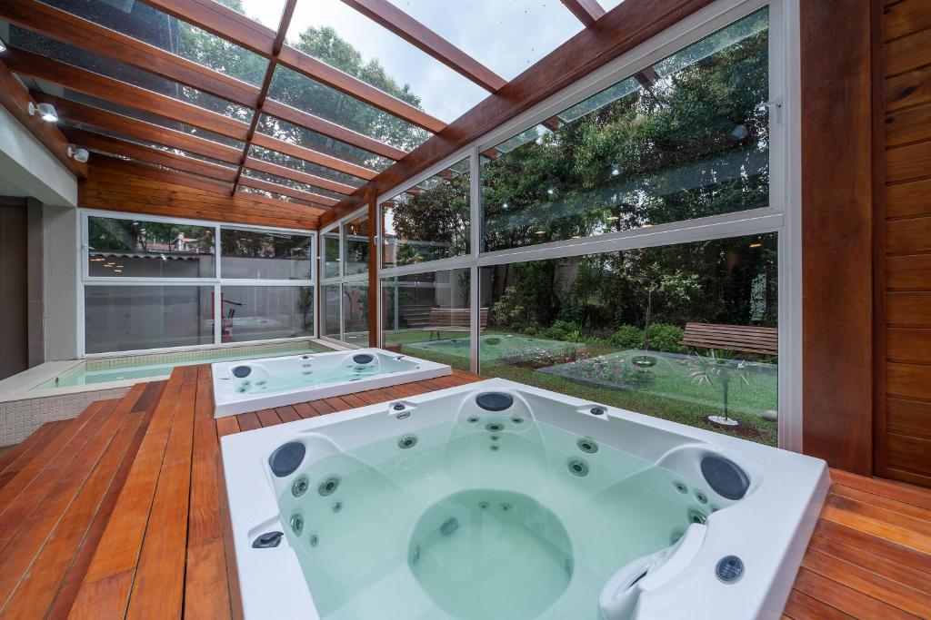 Duas jacuzzis em um espaço coberto com teto de vidro e paredões de vidro com vista para o jardim. Hotéis em Gramado Pet Friendly.