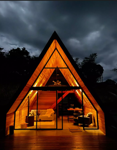 Fachada de Cabanas no interior de São Paulo, com o fundo todo em vidro, iluminada de noite. 