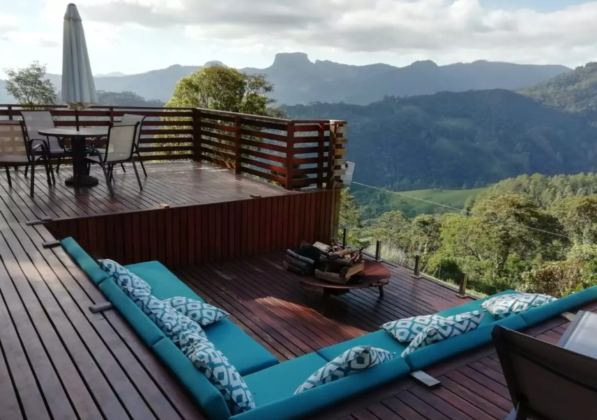 Área de deck com lugar para sentar e lareira de chão, vista para a serra da mantiqueira e pedra do baú.