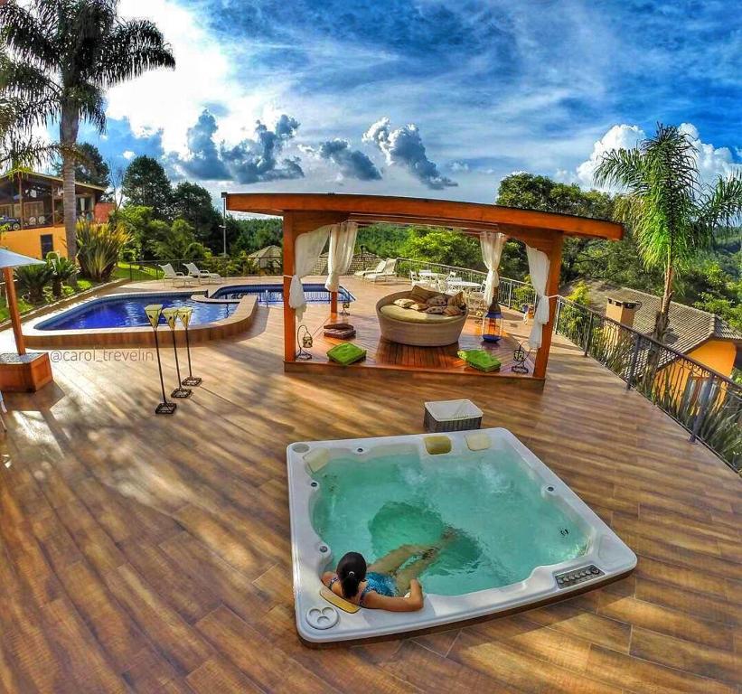 Área externa com jacuzzi e piscina em um lindo deck de madeira, em chalés românticos em Monte Verde.