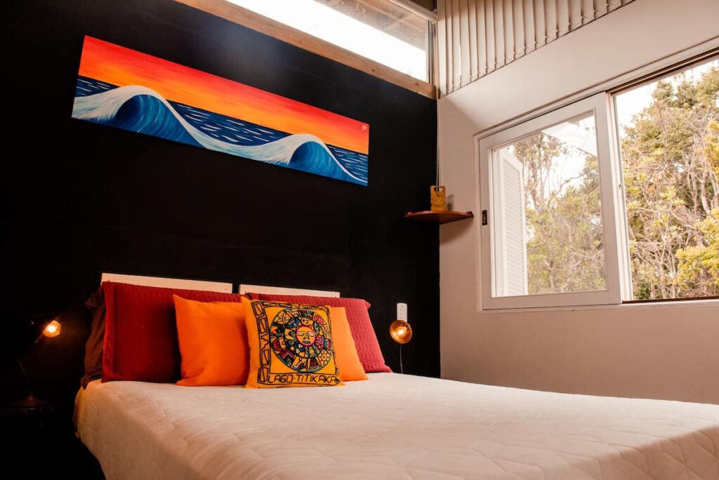 Cama de casal, com parede em preto e quadro colorido como decoração