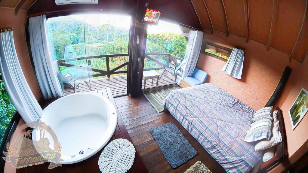 Quarto de casal com hidromassagem e varanda com vista para uma reserva natural. As janelas são grandes em vidro