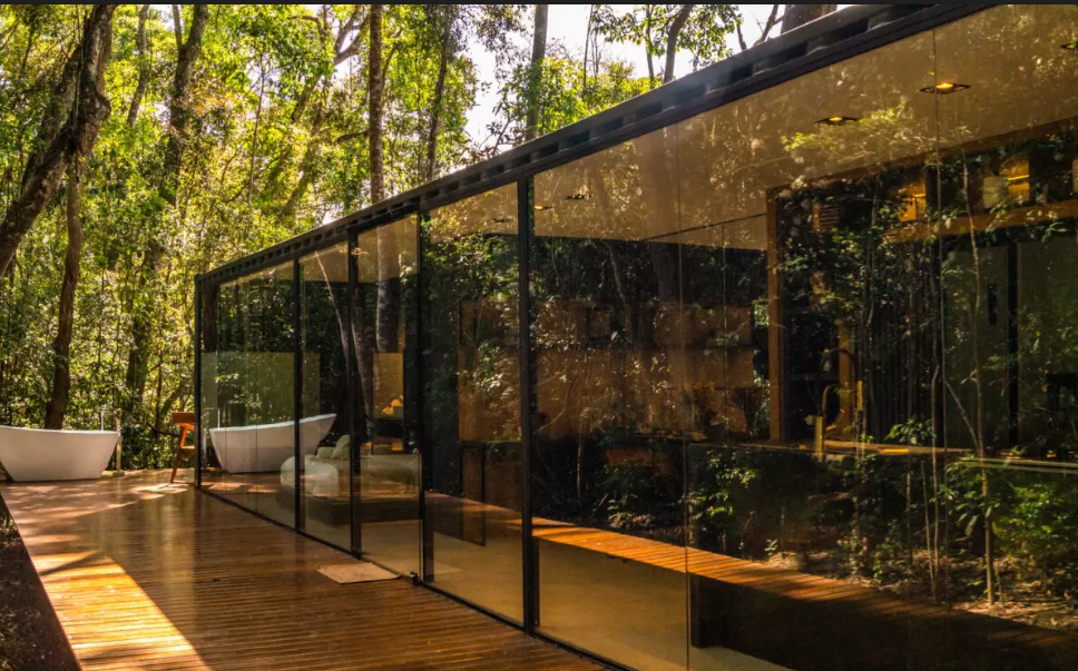 Contêiner com uma lado todo em vidro, em meio à floresta com banheira externa. Chalés românticos em São Roque.