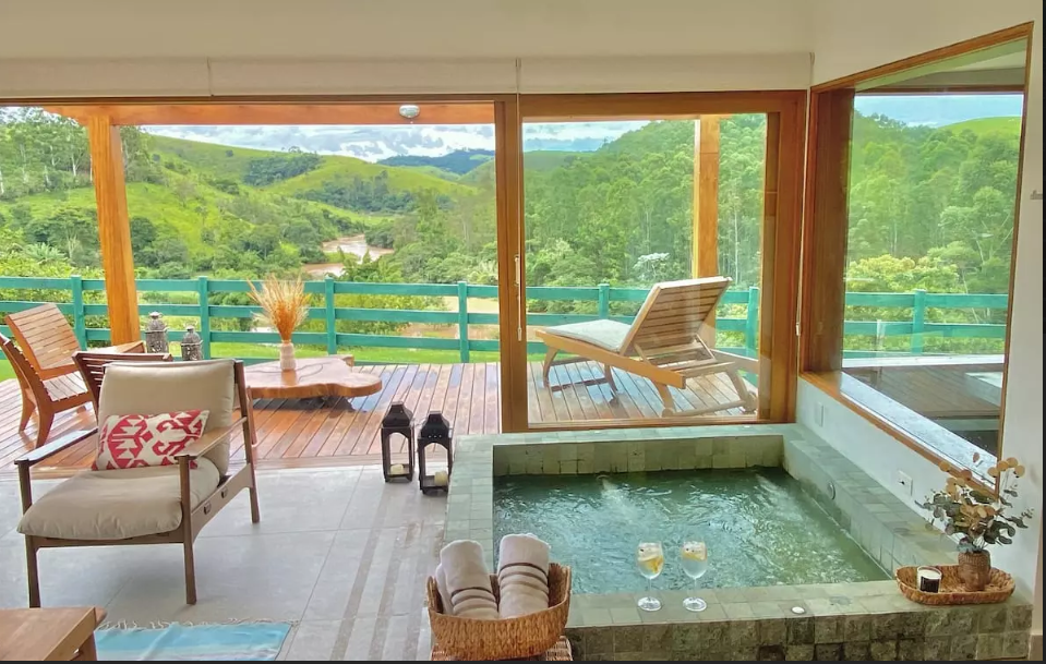 Sala com uma hidromassagem e varanda com vista para as montanhas em Cabanas no interior de São Paulo.