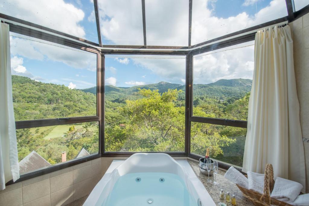 Banheira de hidromassagem em chalés românticos em Monte Verde com teto de vidro e vista para as montanhas.
