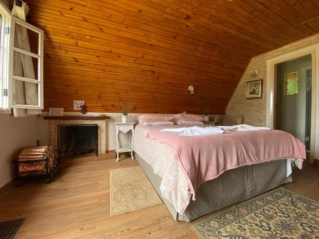 Quarto com cama de casal e lareira em chalés em Monte Verde