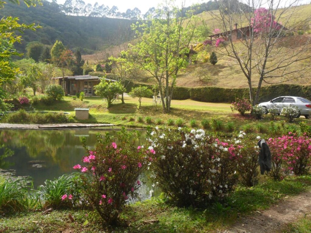 Área externa com jardim bem arborizado e lago