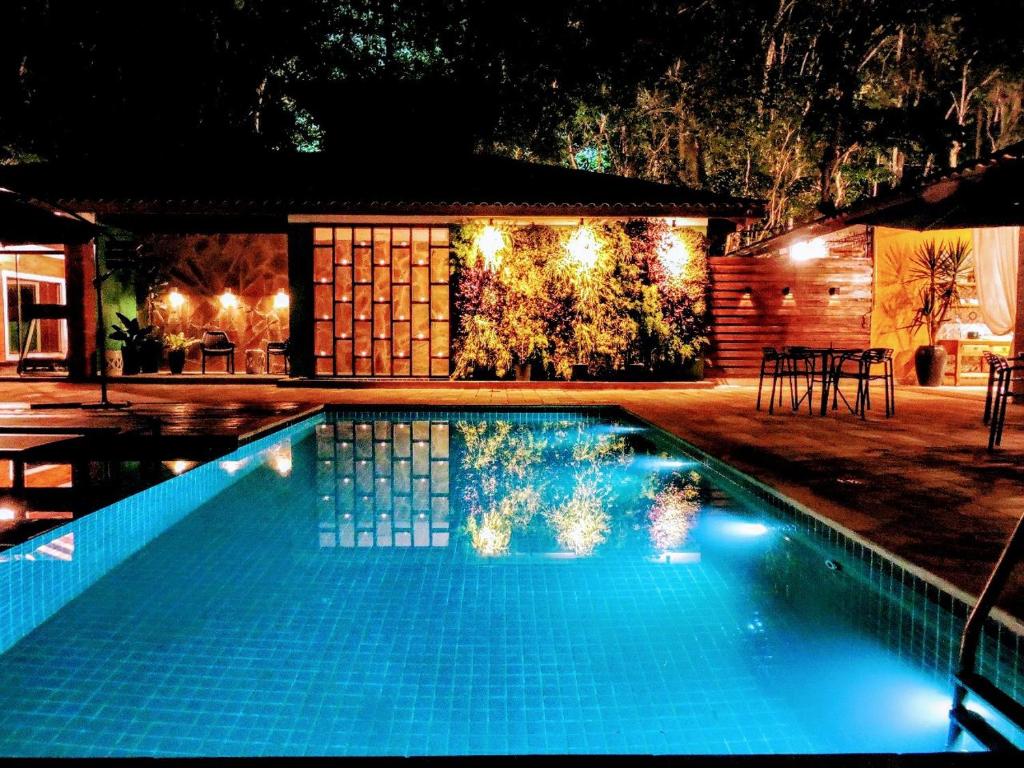 Piscina ao ar livre, de noite, com luzes no jardim. 