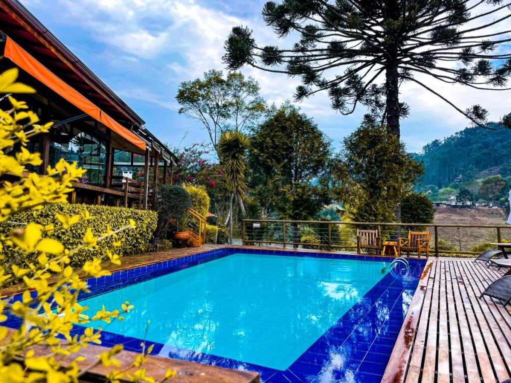 Piscina ao ar livre em pousada petfriendly em Minas Gerais com Auracária ao fundo