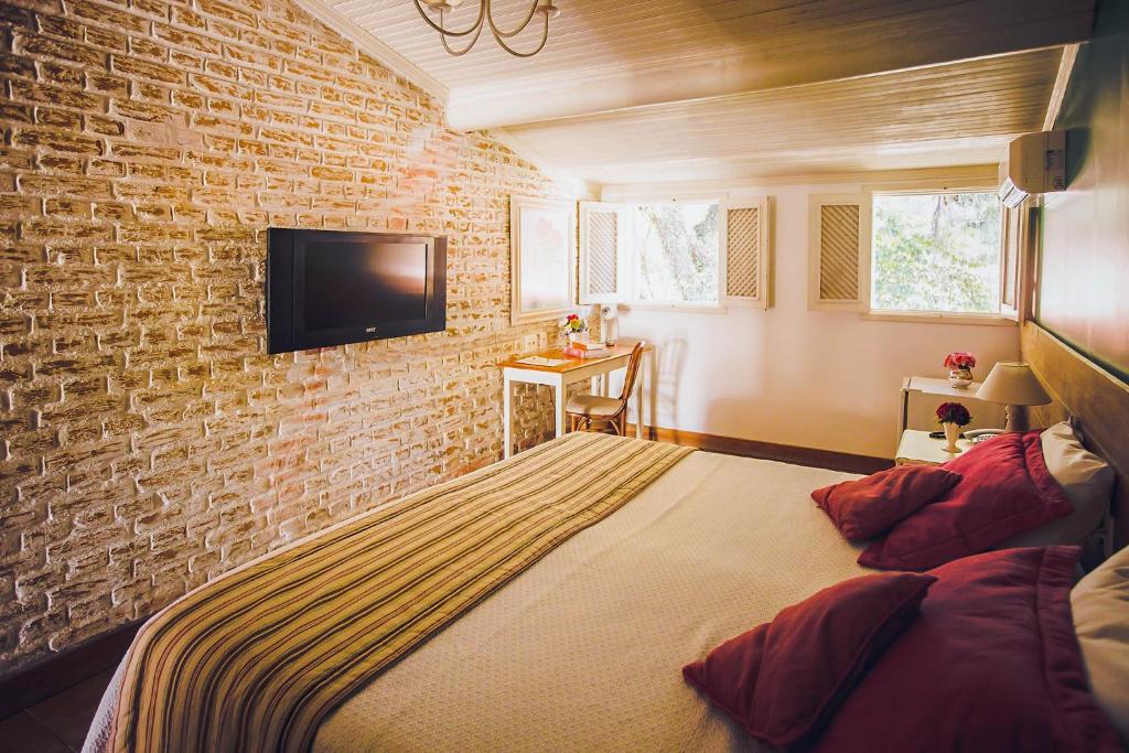Quarto para casal com parede de tijolos aparentes em hotel romântico no interior SP