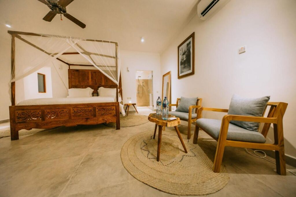 Quarto com cama de casal, poltrona e ventilador de teto em hotéis em Zanzibar