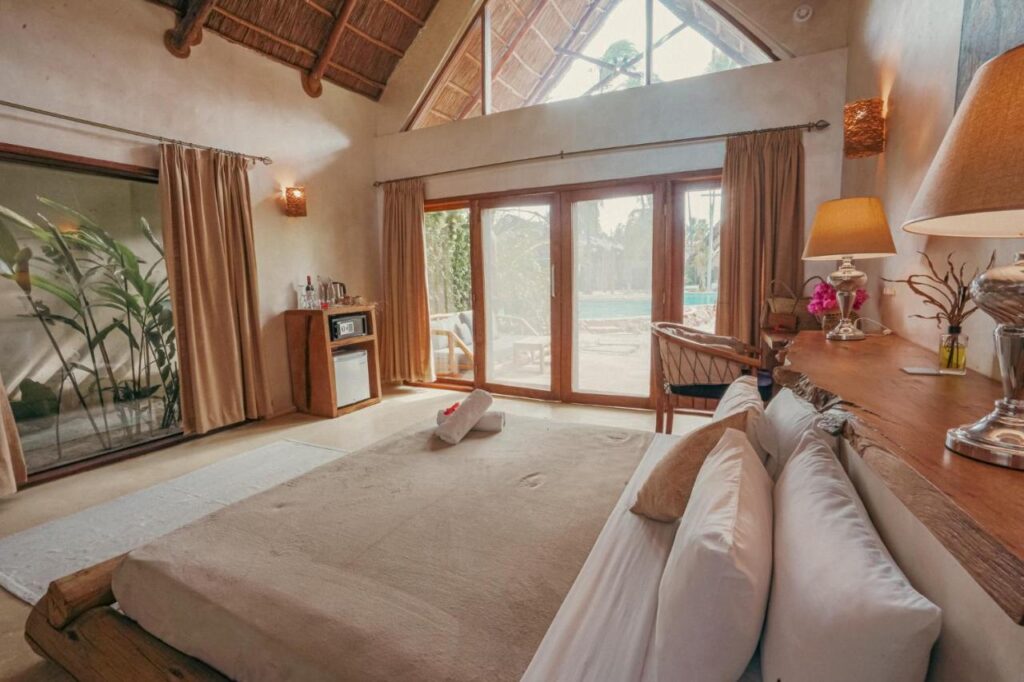 Quarto amplo, com janelões de vidro e decoração mais para o tom do marrom claro. Hotéis em Zanzibar