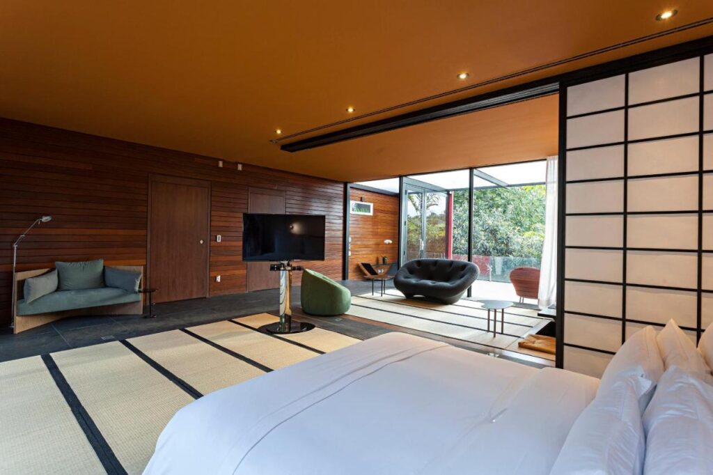 Quarto com cama de casal, varanda e poltronas em hotel romântico no interior SP