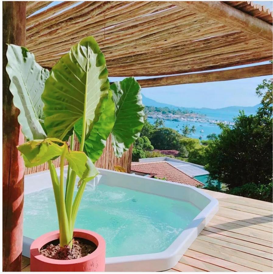 Hidromassagem em deck de madeira, coberto, com vista para o mar bem ao fundo