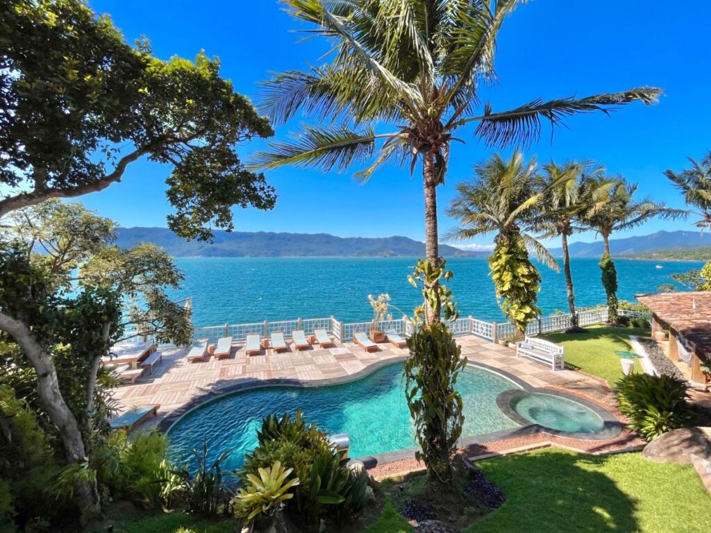 Piscina com vista para o mar, coqueiros e espreguiçadeira