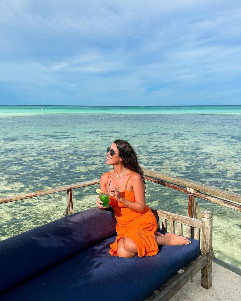 Livia bebendo drink na beira-mar em Onde ficar em Zanzibar