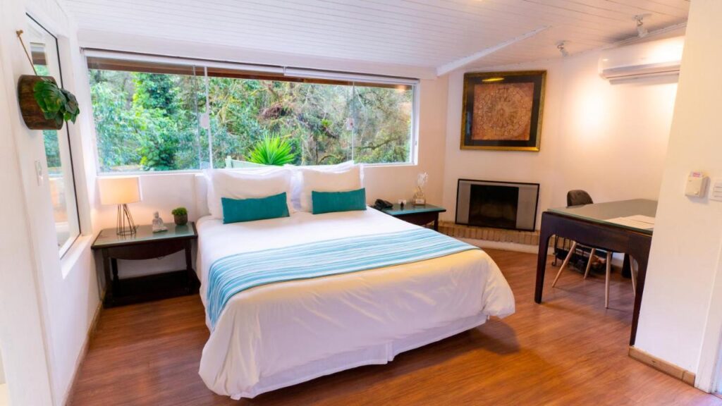 Suíte na Pousada Apple House com cama king, vista para a natureza e lareira.