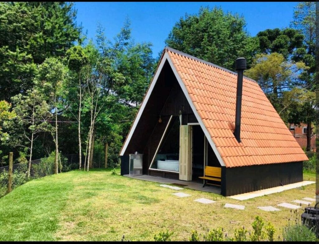 Fachada do chalé palácio em Campos do Jordão. O telhado tem um estilo suíço e há vegetação ao redor.