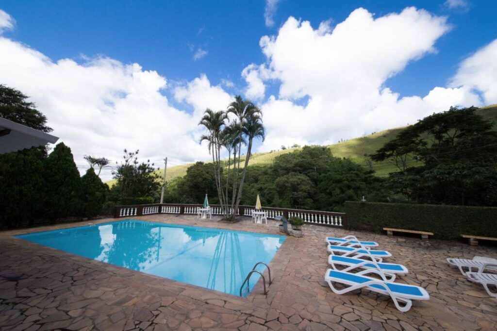 Piscina ao ar livre com vista para as montanhas e espreguiçadeiras em Pousadas Monte Alegre do Sul